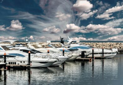 Elegant white yachts docked in a scenic marina with a dramatic cloudy sky and calm waters reflecting the vessels.