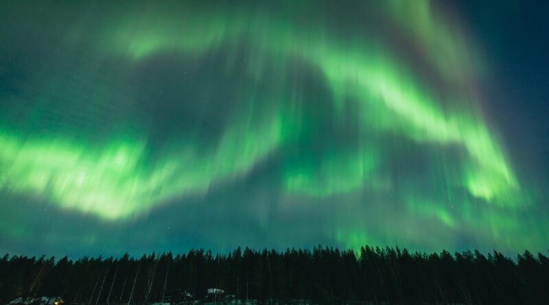 Stunning display of northern lights over a winter forest in Vaala, Finland.